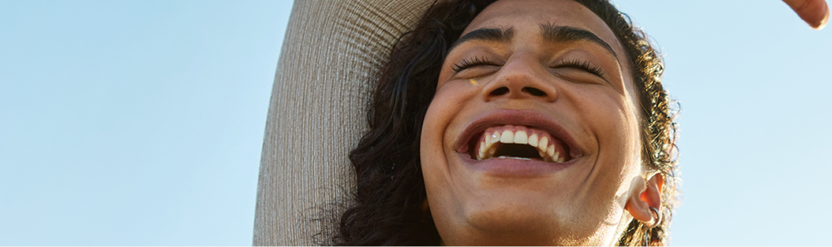 Smiling young woman with a blue sky behind her